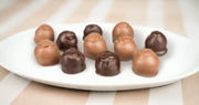 A set of milk and dark chocolate cherry cordials on a white plate. Made by Morkes Chocolates.