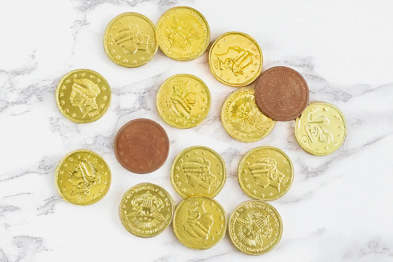 Several Chocolate Gold Coins by Morkes Chocolates spread on a marble floor. Some of the coins are unwrapped