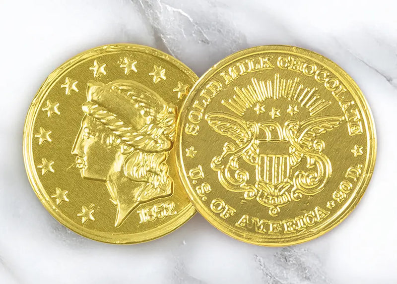 A closeup picture of two Chocolate Gold Coins by Morkes Chocolates placed on a marble floor.