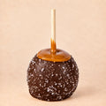 A dark chocolate caramel apple with sea salt from Morkes Chocolate set on a warm beige background