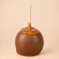 A milk chocolate caramel apple from Morkes Chocolate set on a warm beige background