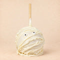 A Halloween-themed caramel apple decorated like a mummy with white chocolate.