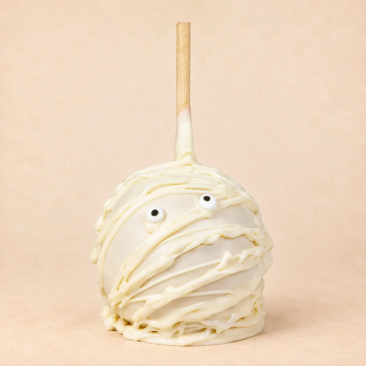 A Halloween-themed caramel apple decorated like a mummy with white chocolate.
