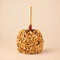A peanut caramel apple from Morkes Chocolates, placed on a warm beige background. 