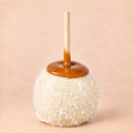 A white chocolate caramel apple with sea salt from Morkes Chocolate set on a warm beige background
